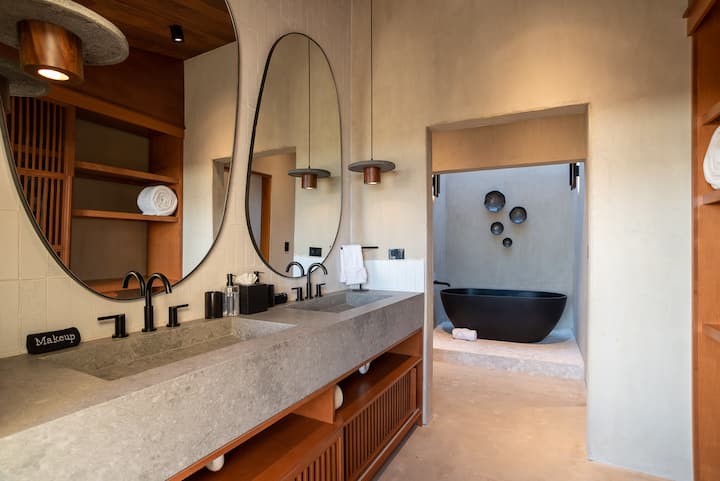 The bath — double vanity, round mirrors, a stone tub